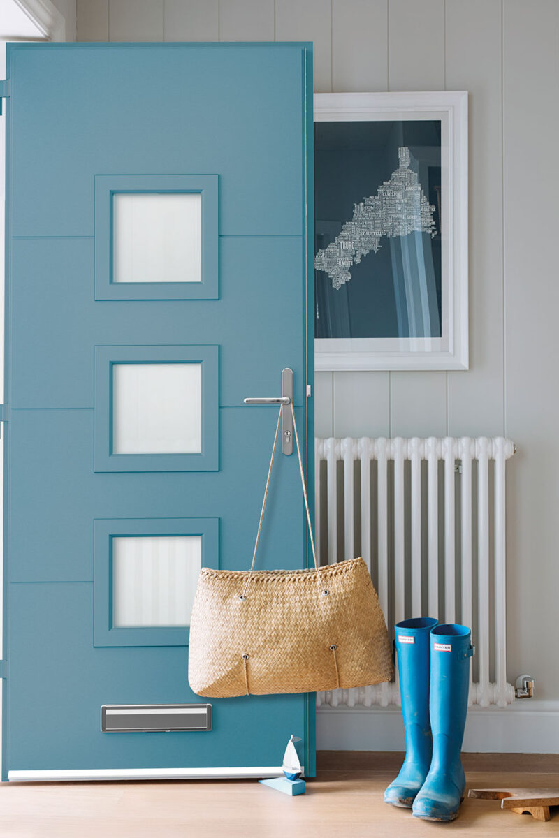 Teal blue composite door with three frosted square panels seen from inside a hallway, with matching blue wellington boots and a woven basket
